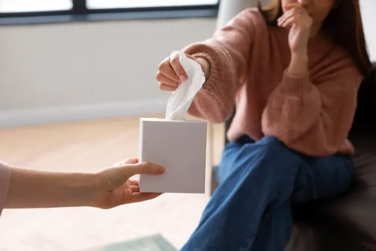 Una persona cogiendo un pañuelo de papel que le ofrece otra persona